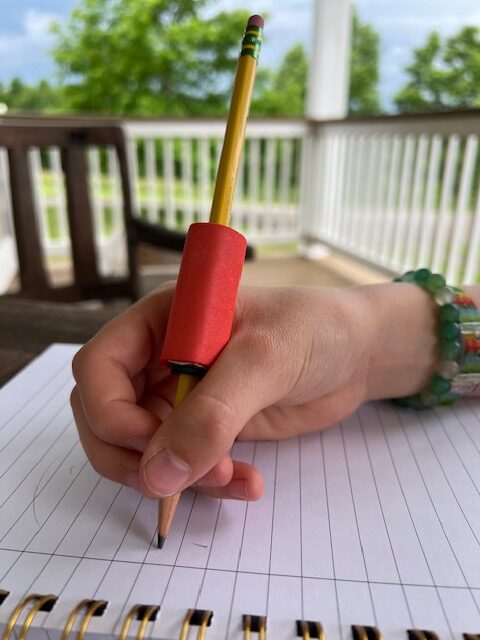 Proper weight placement for a DIY weighted pencil: Resting the coupling nut in the webspace for better handwriting control.